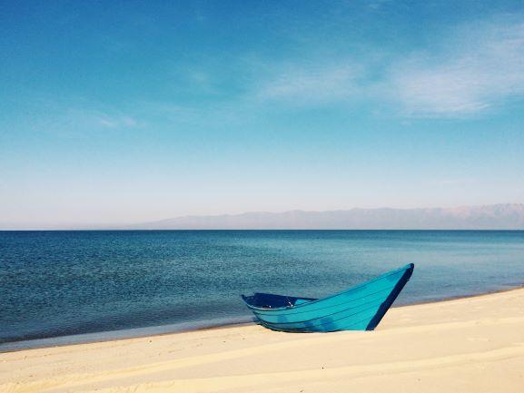 paradiesischer, weißer Sandstrand in Kuba, Blick auf das Meer, den Horizont und ein blaues Boot  