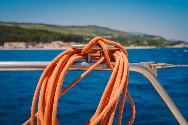 Blick von einer Yacht auf die malerische Küste Martiniques, das blaue Meer und ein oranges Seil im Fokus 