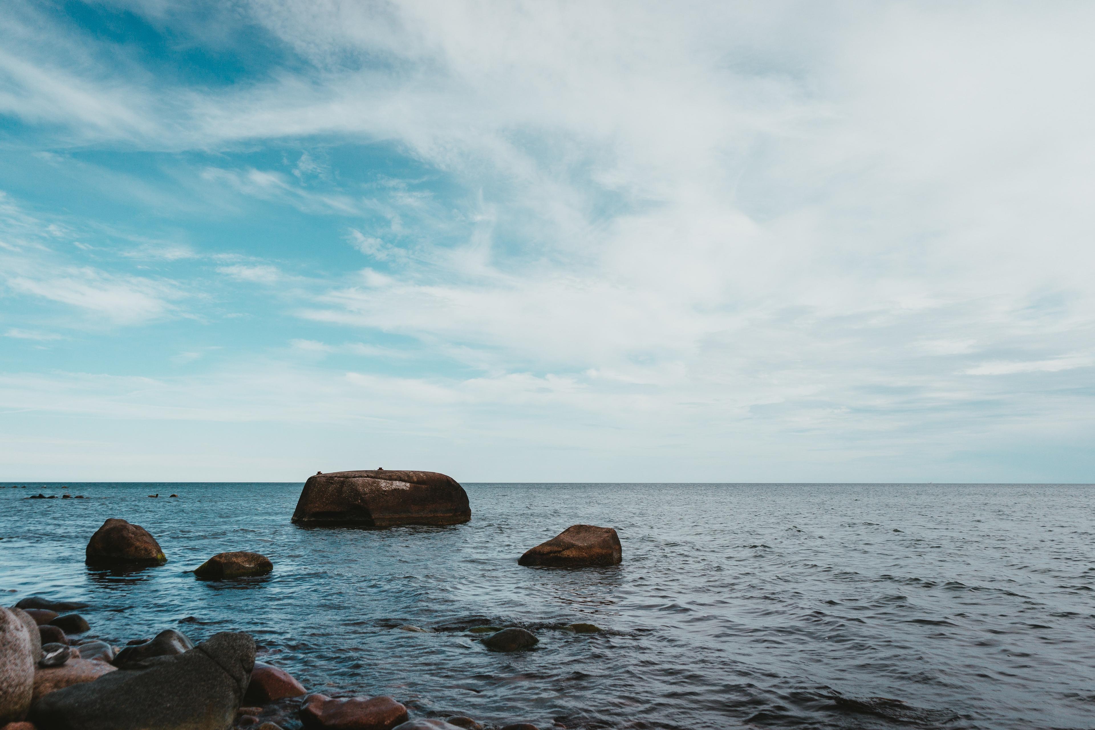 Blick auf die Ostsee und den Horizont sowie dunkle Steine im Wasser