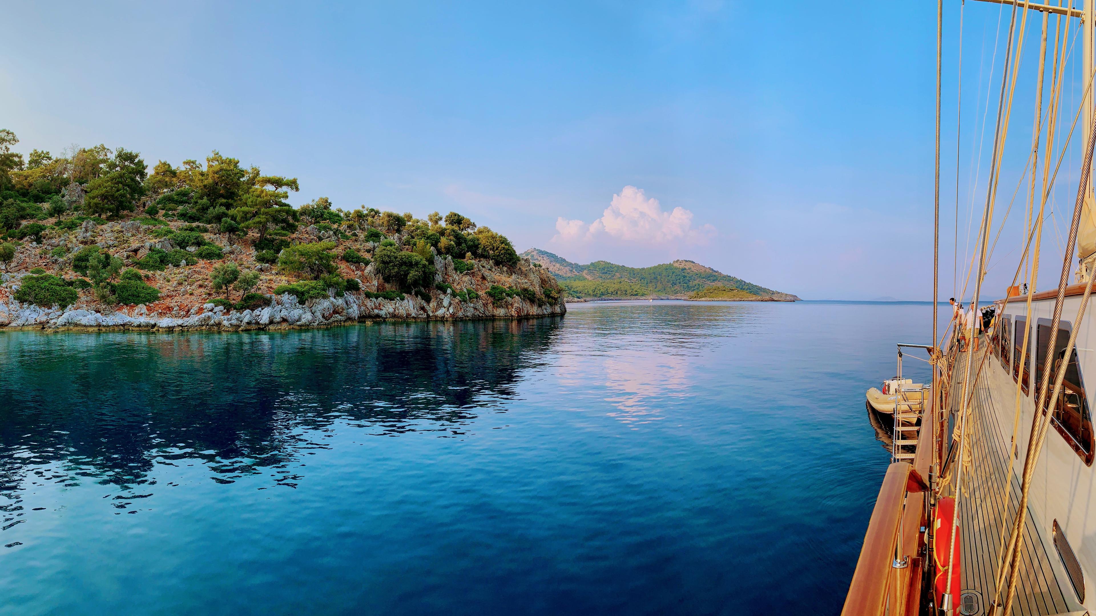 Blick von einer großen Yacht auf steinige Buchten und klares, blaues Wasser