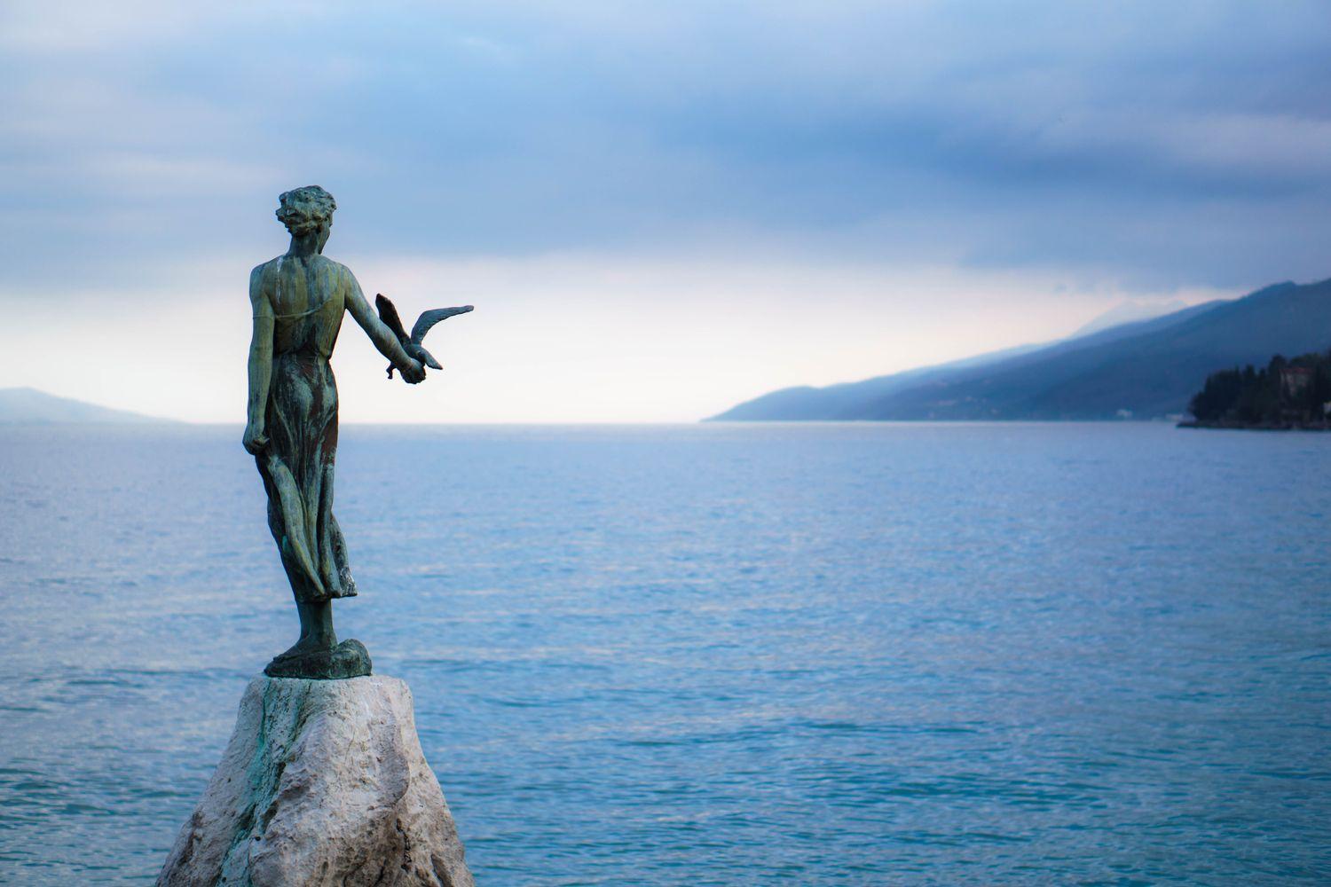 Statue auf einem Stein an der Küste Kroatiens und Blick auf das Meer und den Horizont