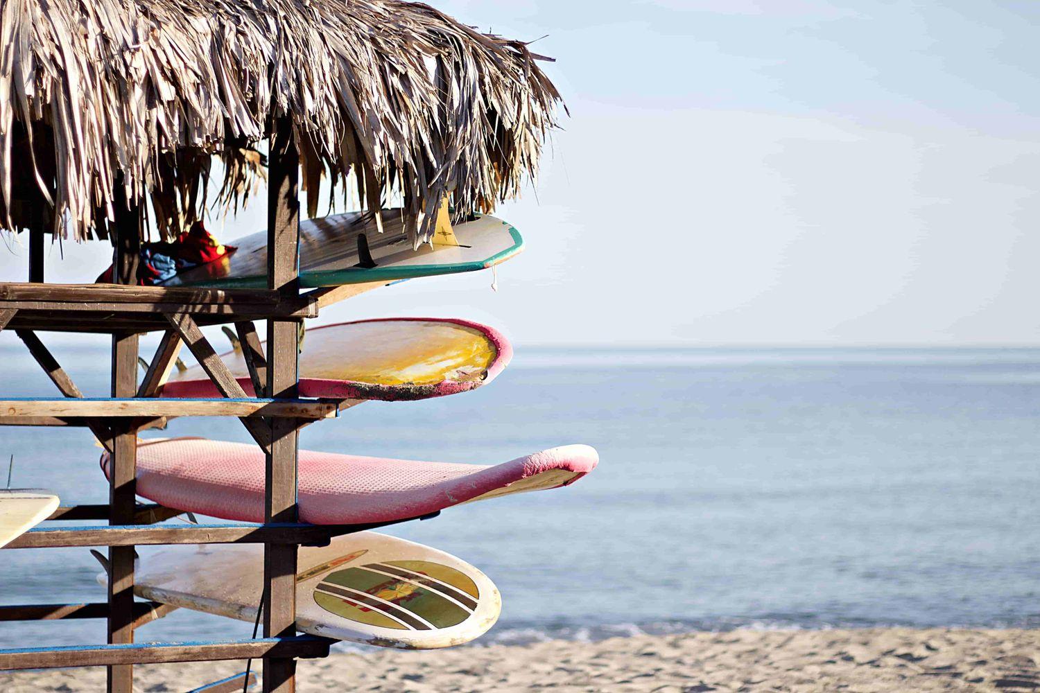 mehrere bunte Surfbretter in einer exotischen Hütte am weißen Strand von Martinique  