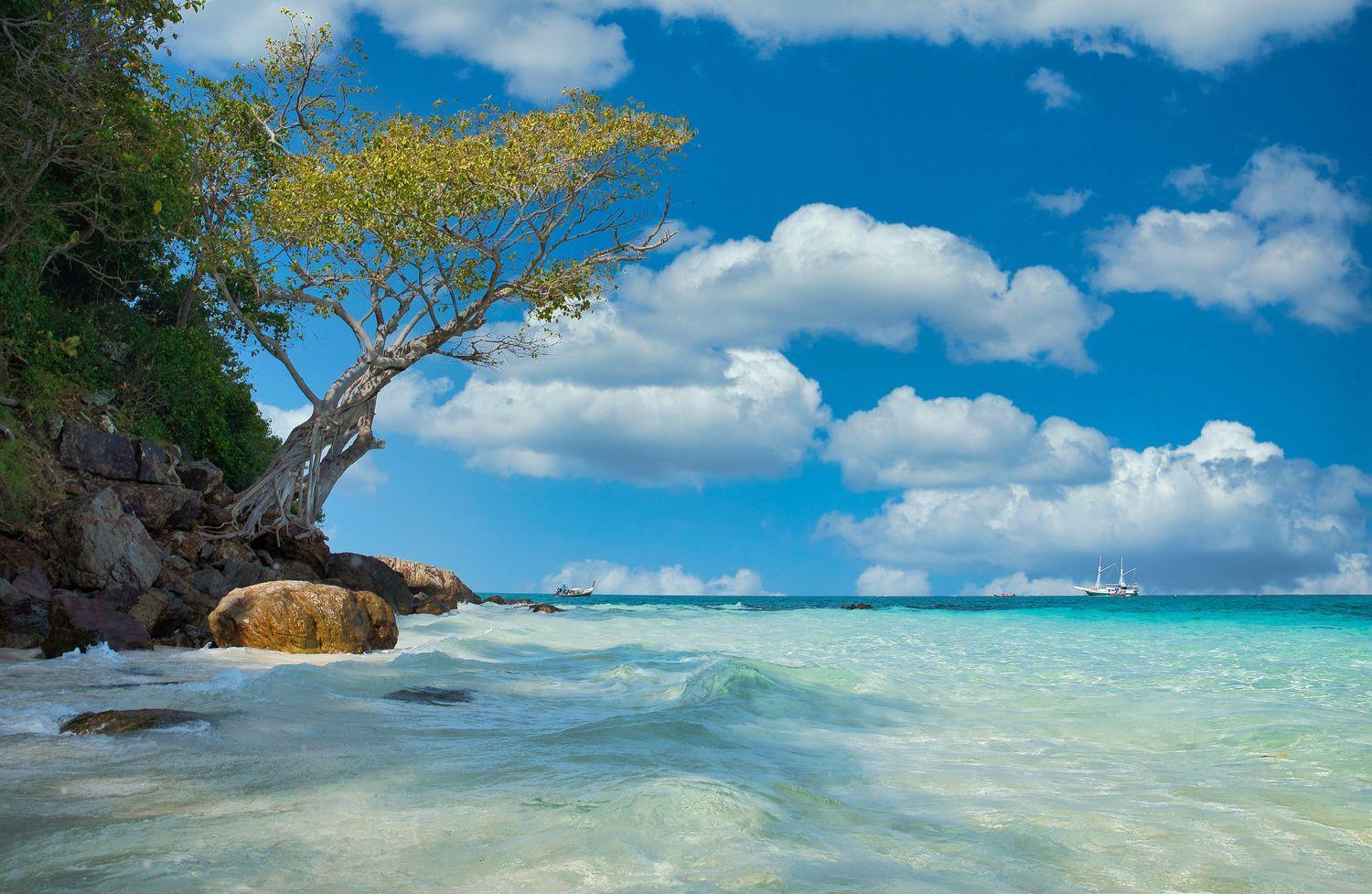 Strand mit Felsen, Baum und türksiblauem Wasser